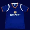 front view of Manchester United away blue retro jersey (1984) with vintage stripes.
